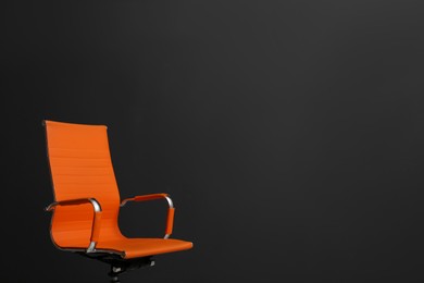 Photo of Comfortable office chair on black background. Space for text