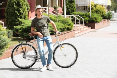 Photo of Handsome young man with bicycle on city street