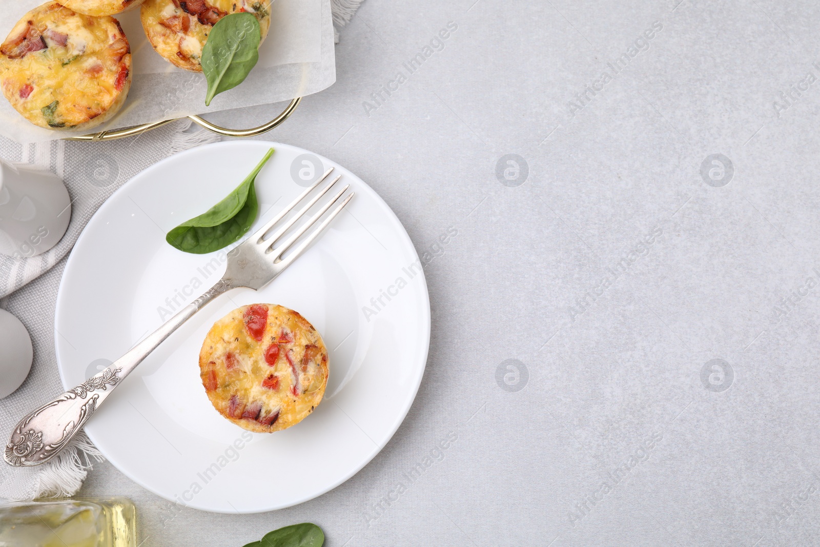 Photo of Freshly baked bacon and egg muffins with cheese served on light gray table, flat lay. Space for text