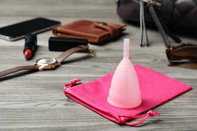 Menstrual cup and different women's accessories on wooden table