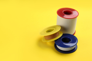 Photo of Sticking plaster rolls on yellow background. Space for text