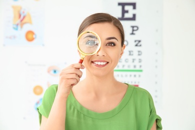 Photo of Young woman with magnifier visiting ophthalmologist