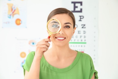 Young woman with magnifier visiting ophthalmologist