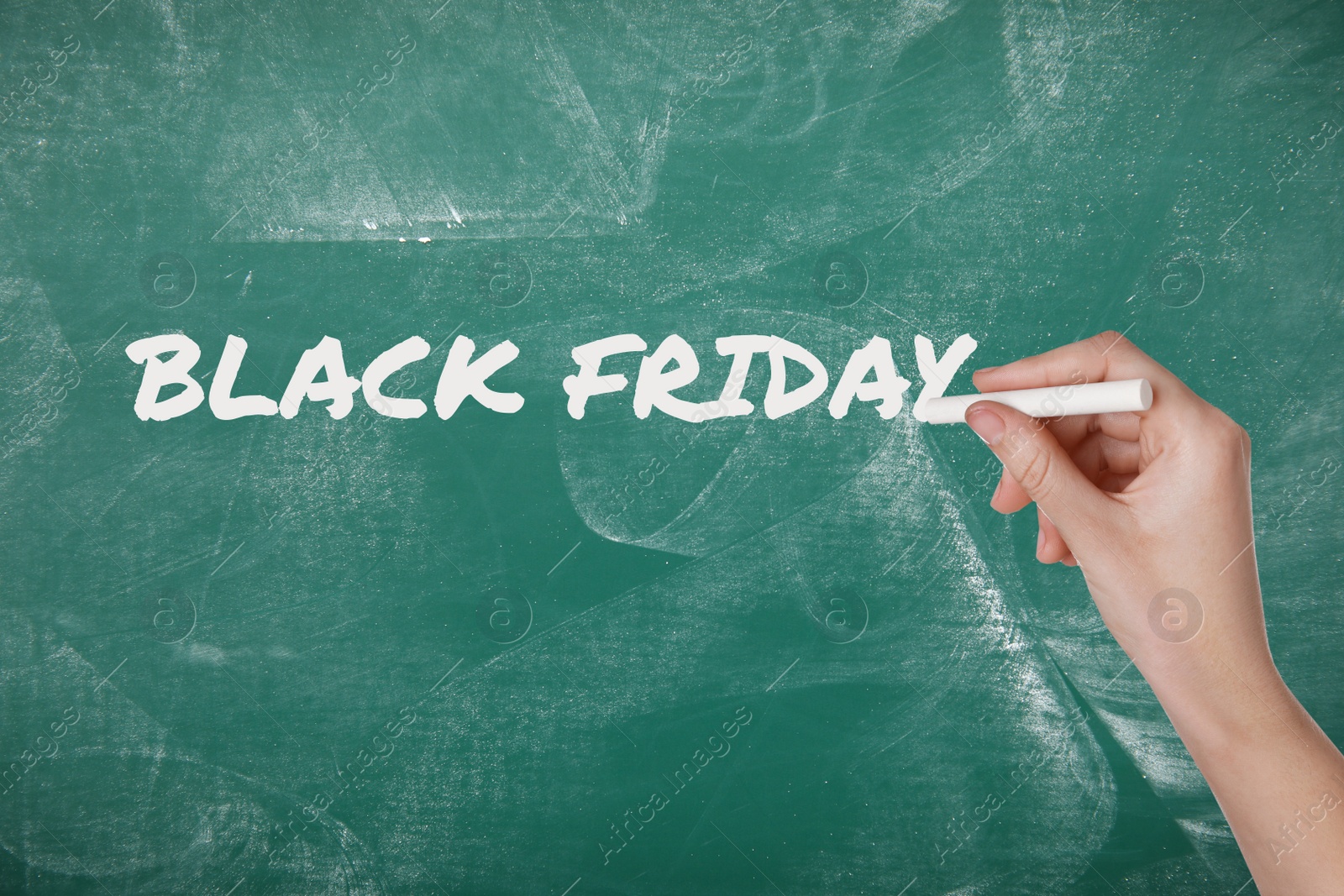 Image of Woman writing text BLACK FRIDAY on green chalkboard, closeup