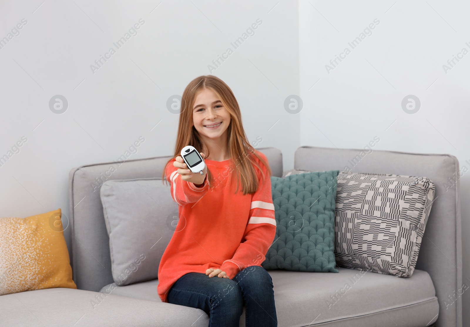 Photo of Teen girl holding digital glucometer at home. Diabetes control