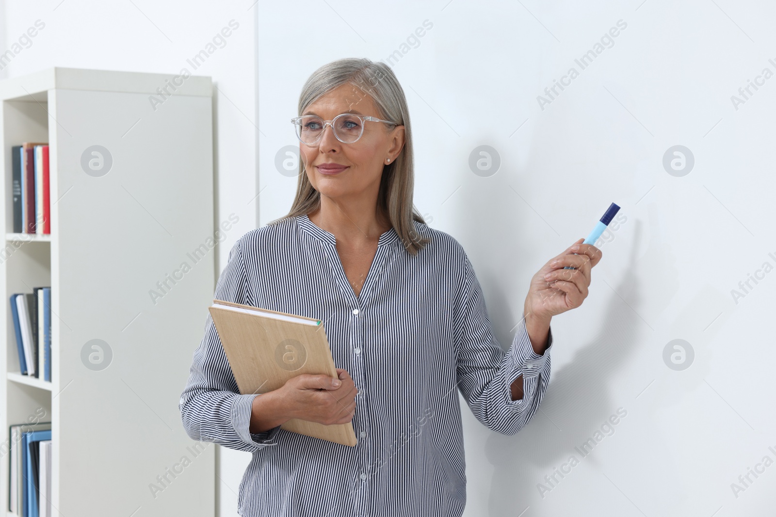 Photo of Professor giving lecture near whiteboard in classroom