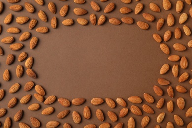 Photo of Frame made of organic almond nuts on color background, top view. Space for text