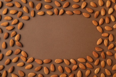 Frame made of organic almond nuts on color background, top view. Space for text