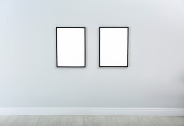 Frames with empty canvases on wall in modern art gallery. Mockup for design