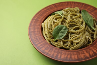 Photo of Tasty pasta with spinach on green table, closeup