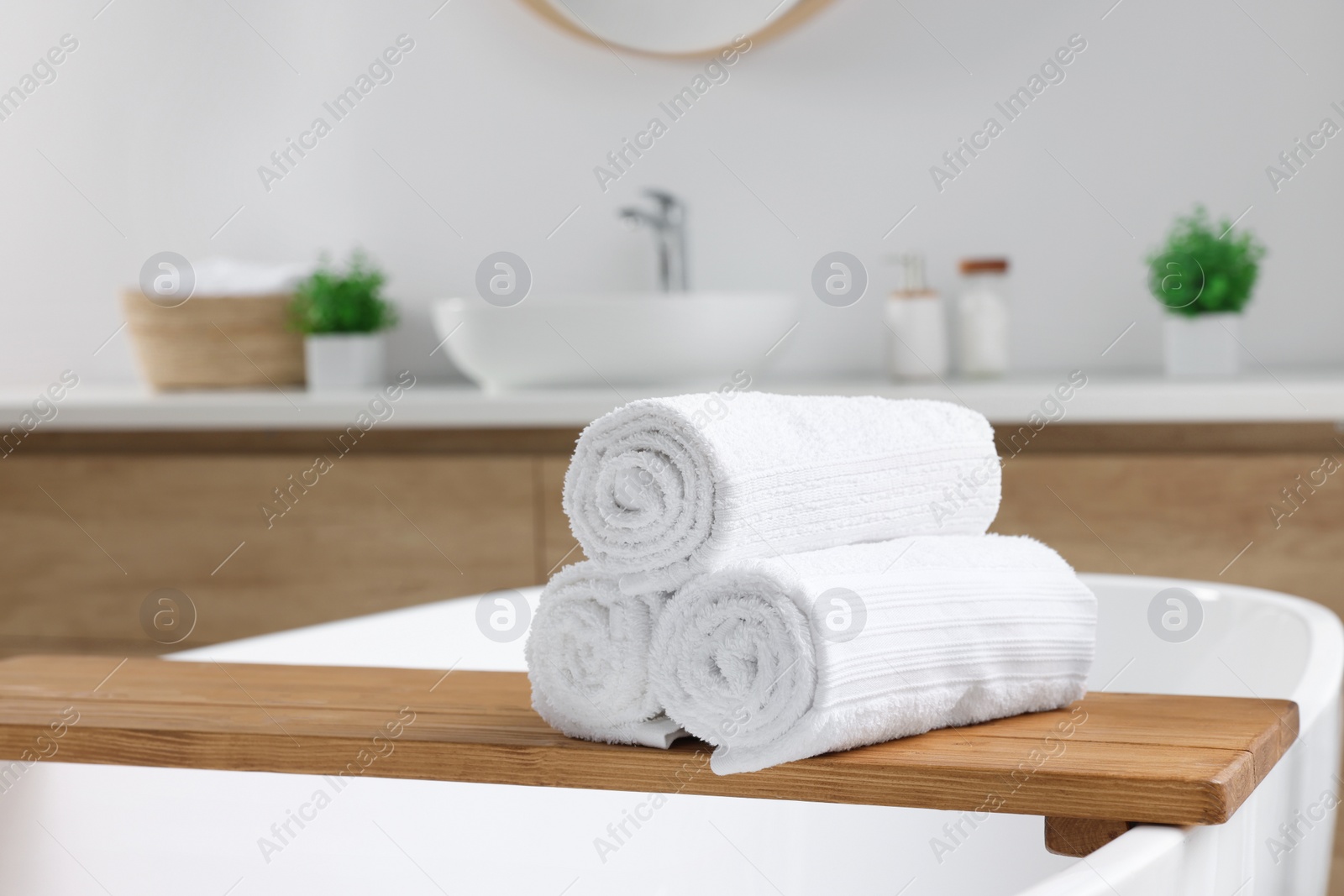 Photo of Rolled white towels on tub in bathroom. Space for text