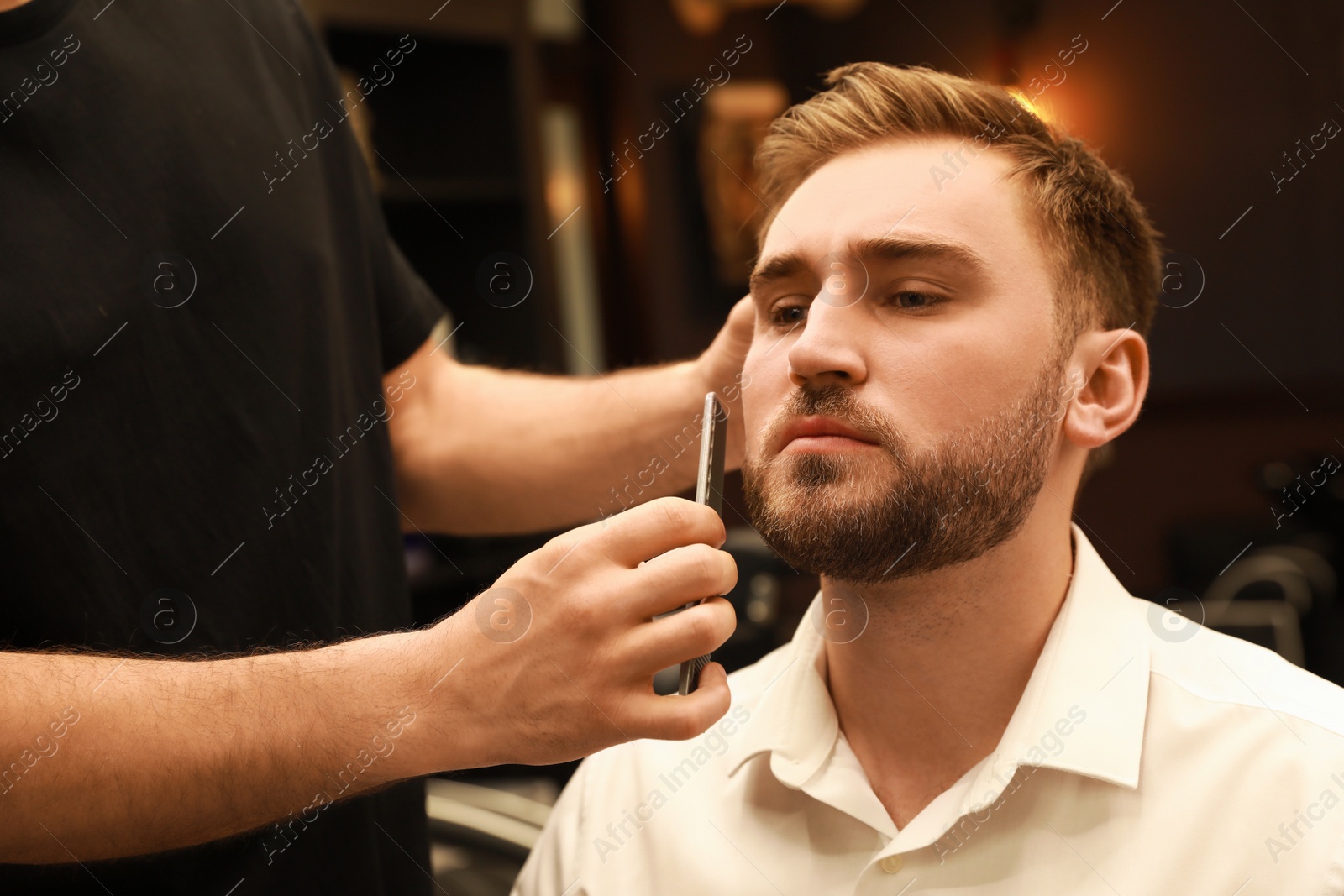 Photo of Professional hairdresser working with client in barbershop