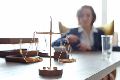 Photo of Scales on table and lawyer in office