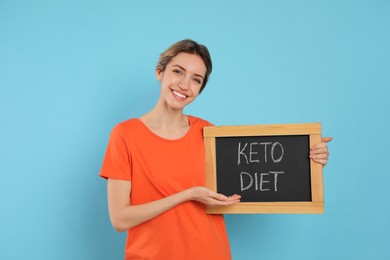 Photo of Woman holding blackboard with phrase Keto Diet on light blue background
