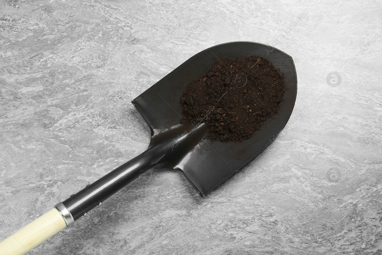 Metal shovel with fertile soil on gray textured surface, top view Photo of Metal shovel with fertile soil on gray textured surface, top view