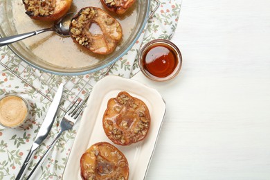 Photo of Delicious quinces baked with honey and walnuts on white wooden table, flat lay