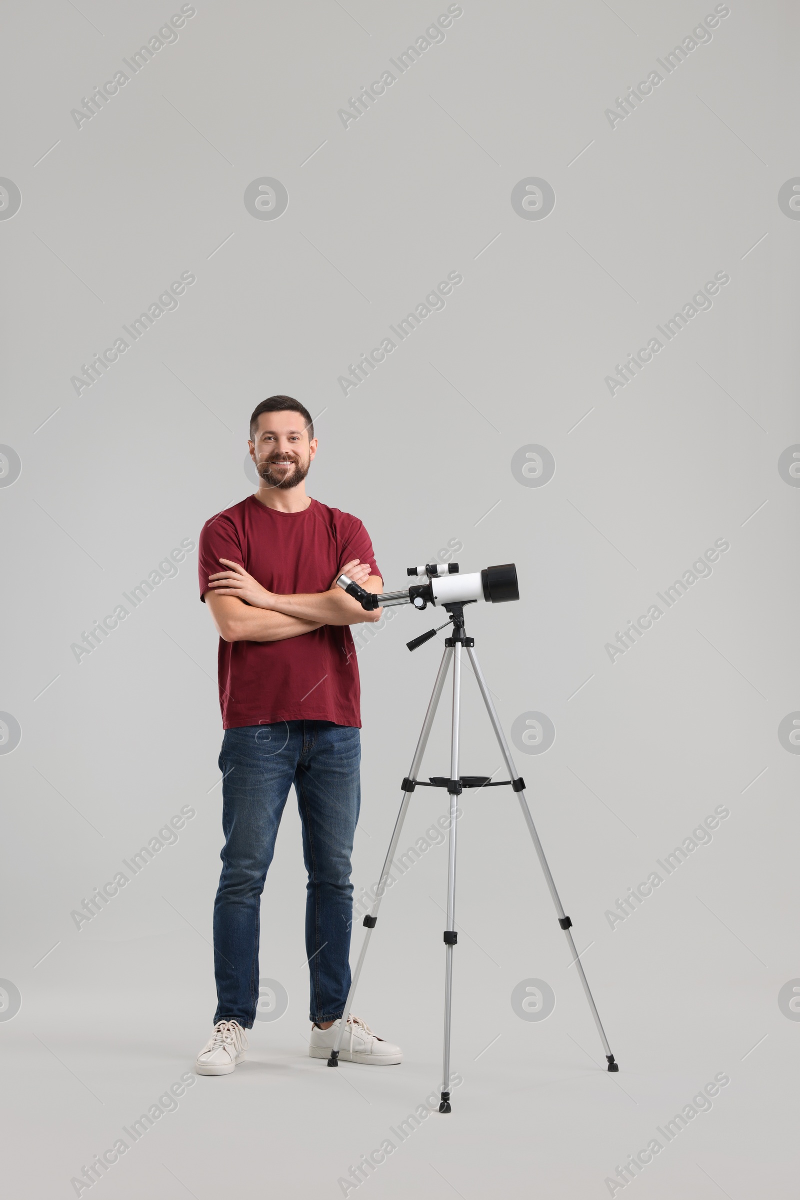 Photo of Happy astronomer with telescope on light grey background