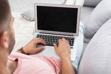 Photo of Man in casual clothes using laptop on sofa at home