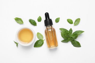 Photo of Essential basil oil with fresh leaves on white background, flat lay