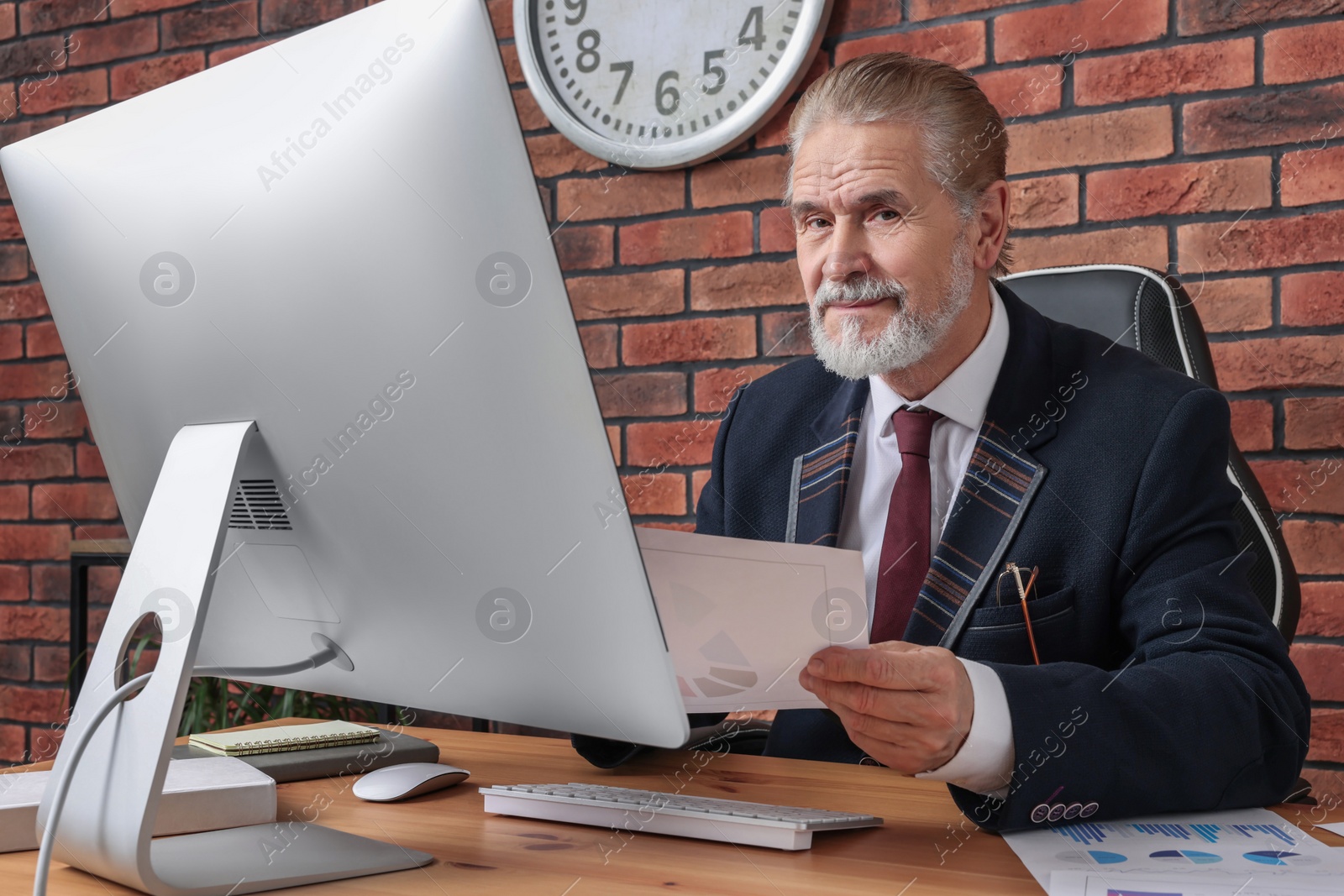 Photo of Happy senior boss working in his office