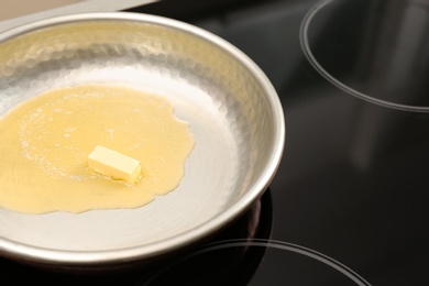 Photo of Frying pan with melted butter on stove, closeup. Space for text