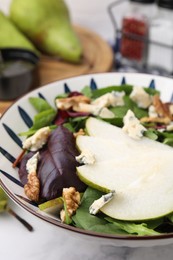 Delicious pear salad in bowl on marble table, closeup