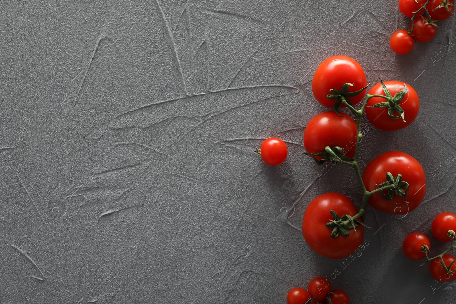 Photo of Food photography. Delicious ripe tomatoes on grey textured table, flat lay with space for text