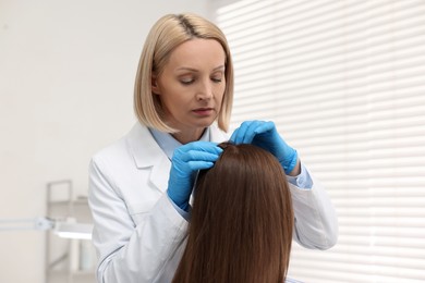 Photo of Trichologist in gloves examining patient`s hair in clinic