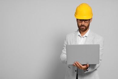 Photo of Professional engineer in hard hat with laptop on white background, space for text