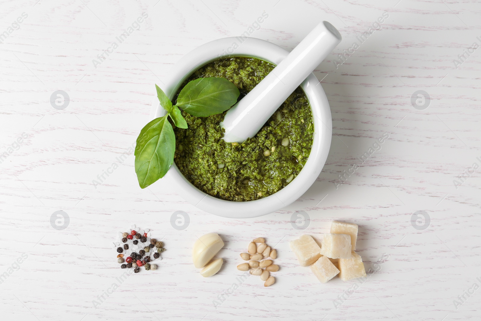 Photo of Flat lay composition with mortar of tasty pesto sauce and pestle on wooden table