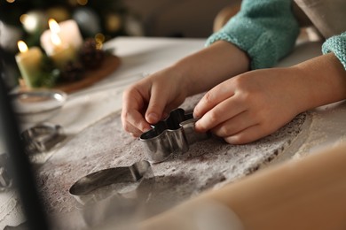 Photo of Little child making Christmas cookies at white table, closeup