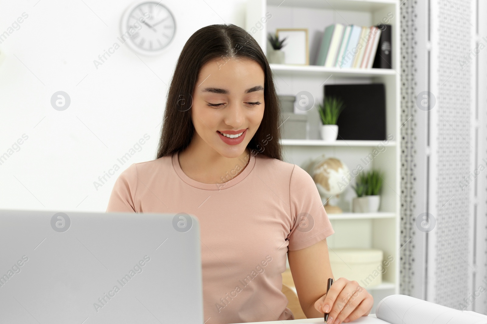 Photo of Home workplace. Happy woman working on laptop in room