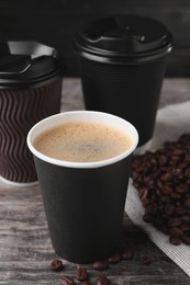 Photo of Coffee to go. Paper cups with tasty drink and roasted beans on wooden table