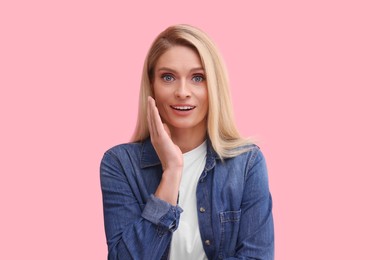 Photo of Portrait of surprised middle aged woman with blonde hair on pink background