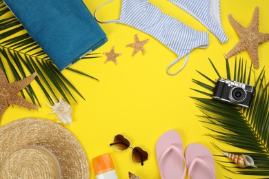 Frame of beach objects on yellow background, flat lay. Space for text