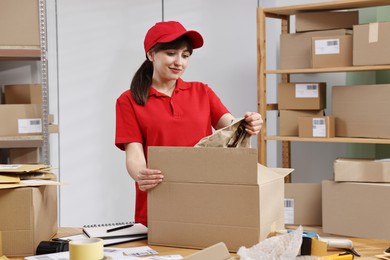 Photo of Post office worker packing parcel at wooden table indoors