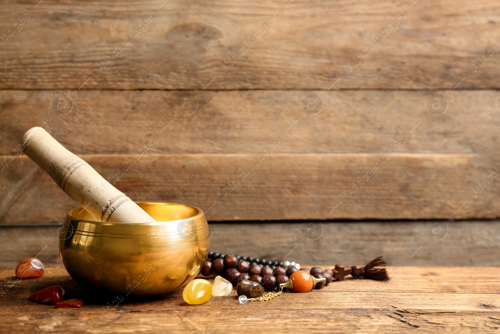 Photo of Composition with golden singing bowl on wooden table, space for text. Sound healing