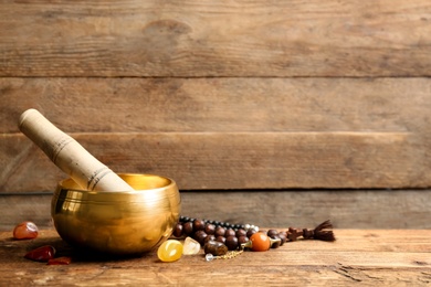Photo of Composition with golden singing bowl on wooden table, space for text. Sound healing