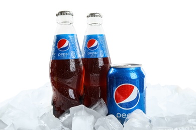 MYKOLAIV, UKRAINE - FEBRUARY 11, 2021: Glass bottles and can of Pepsi on ice cubes against white background