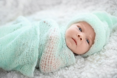 Adorable newborn baby in warm hat lying on bed