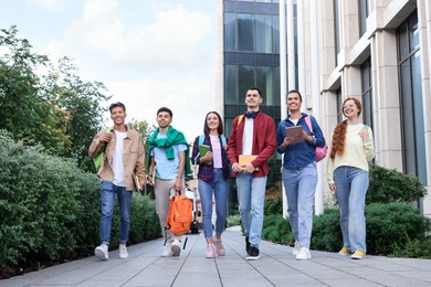 Photo of Group of happy students walking together outdoors, low angle view