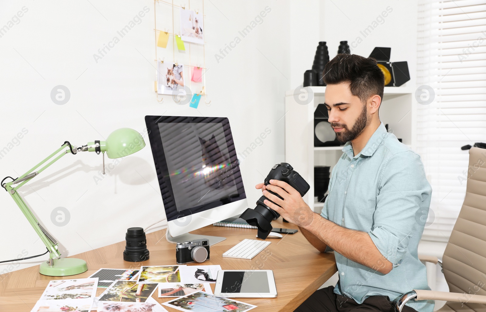 Photo of Professional photographer with camera working at table in office