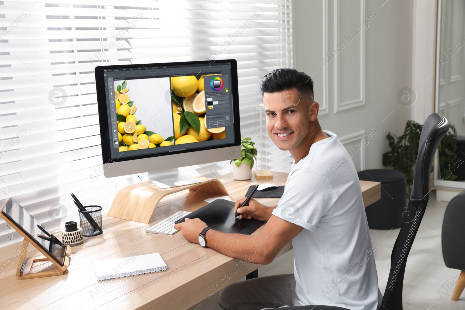 Photo of Professional retoucher working on graphic tablet at desk in office