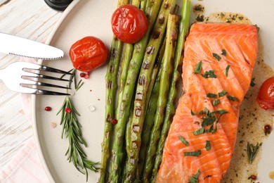 Photo of Tasty grilled salmon with tomatoes, asparagus and spices served on table, top view