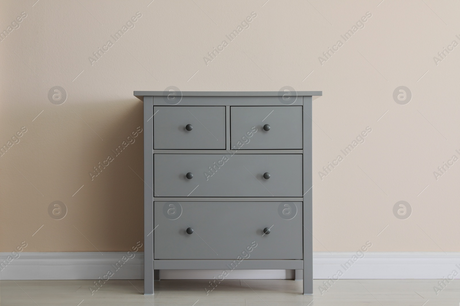 Photo of Grey chest of drawers near beige wall