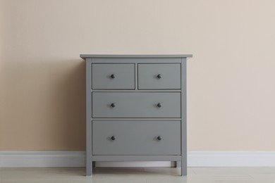 Photo of Grey chest of drawers near beige wall