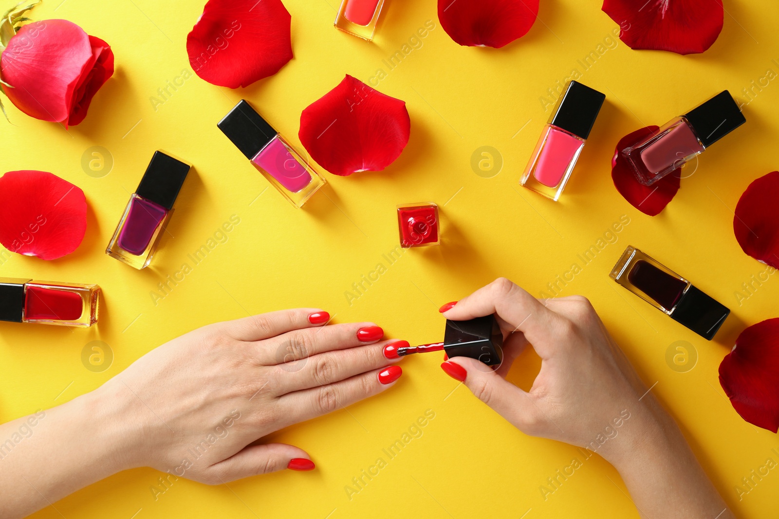 Photo of Woman applying bright nail polish on color background, top view