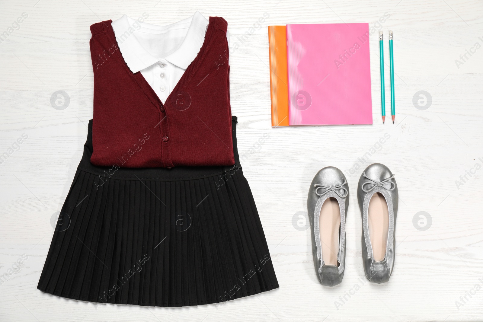 Photo of School uniform and stationery on white wooden background, top view