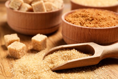 Photo of Different types of sugar on wooden table, closeup