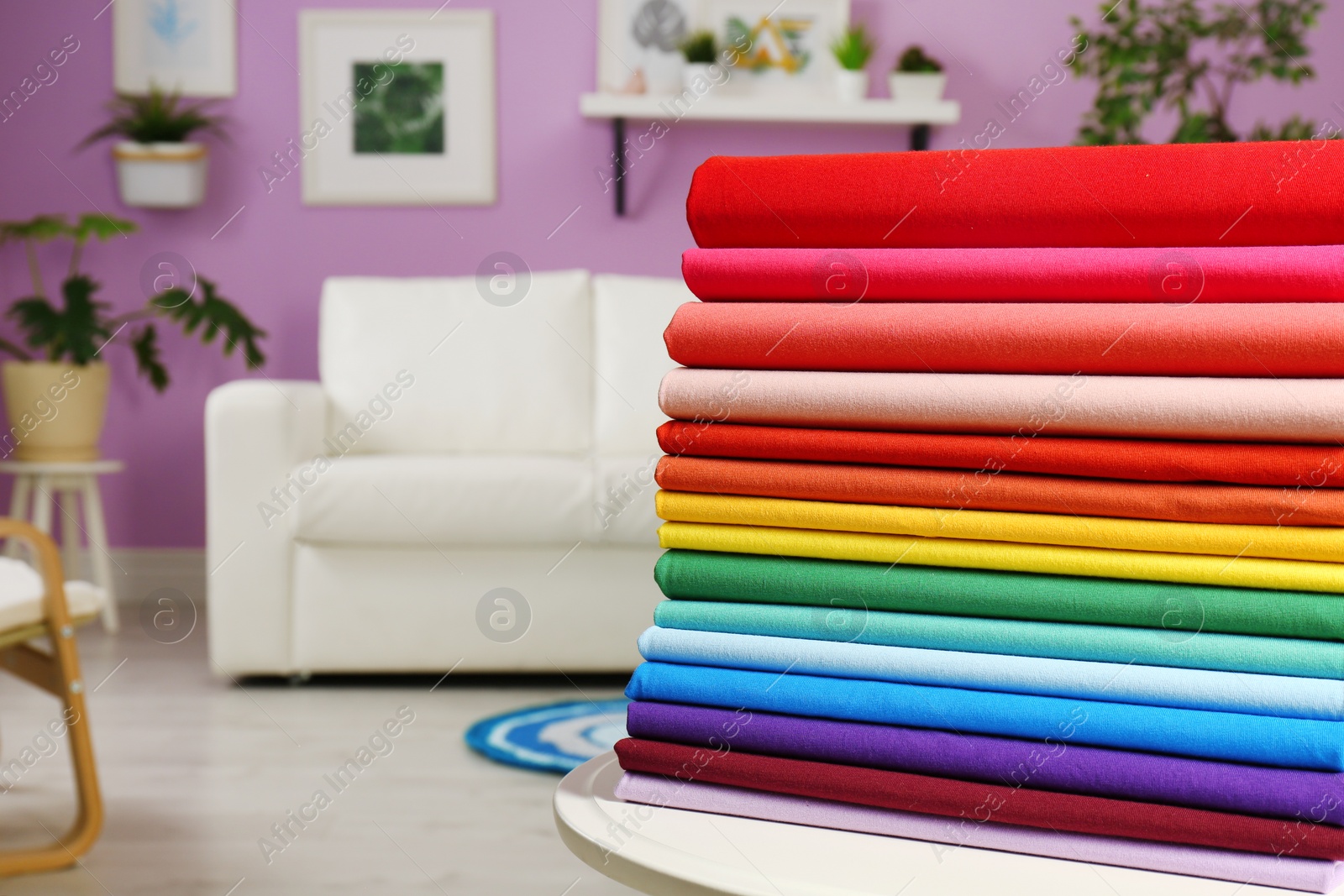 Photo of Pile of colorful t-shirts on table in living room